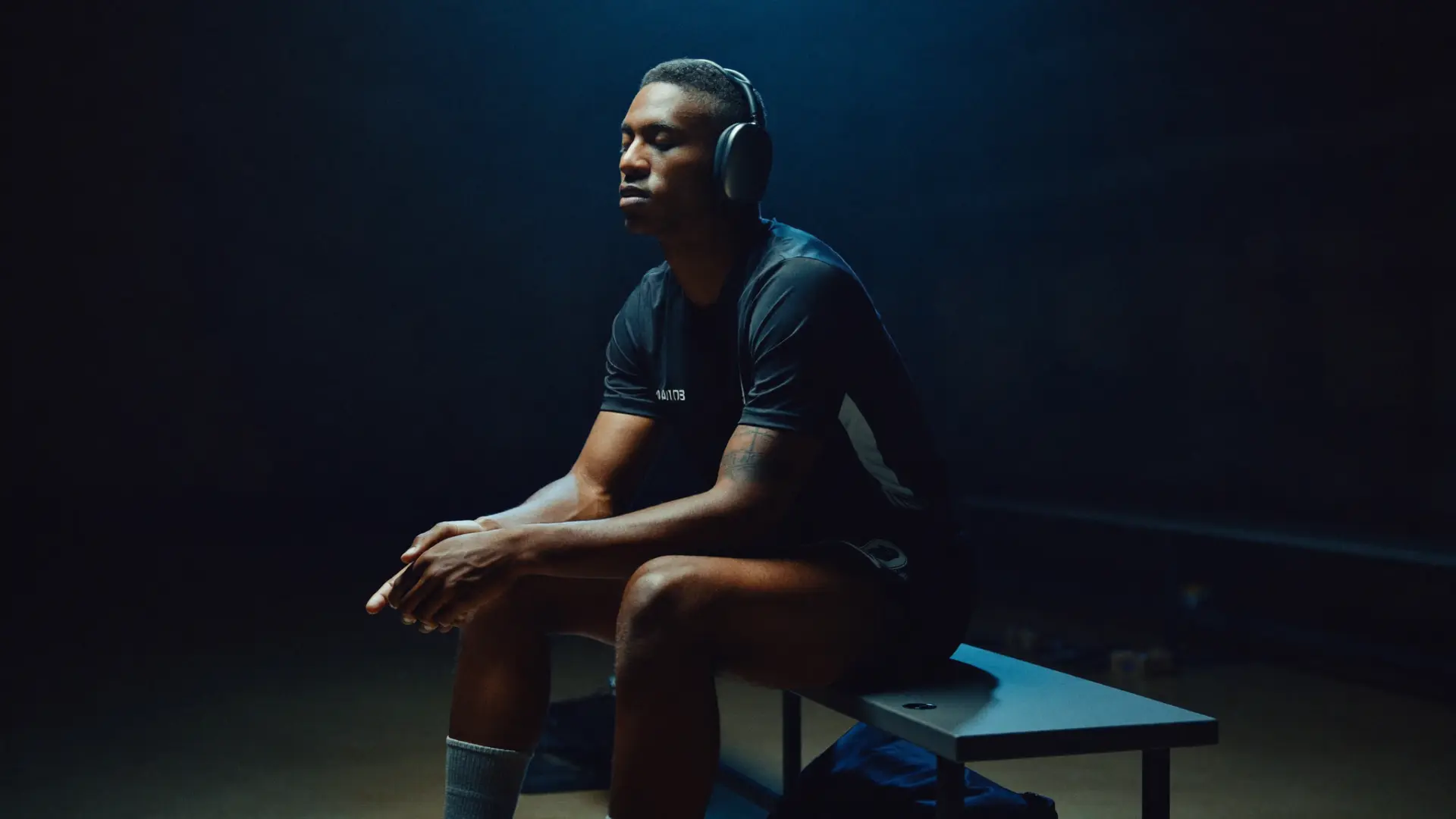 Athlete with headphones, eyes closed, alone in the dressing room before competition