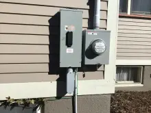 Exterior electrical meter and service equipment installed beside a home
