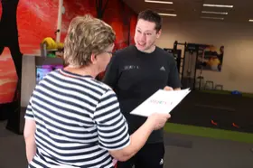 Een coach in gesprek met een lid over het trainingsprogramma bij Sporty-x