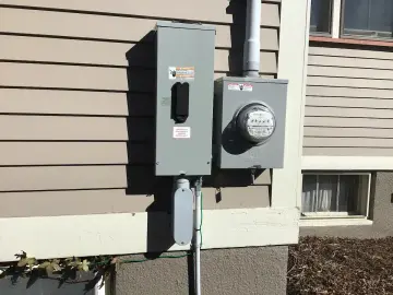 Exterior electrical meter and service equipment beside a home