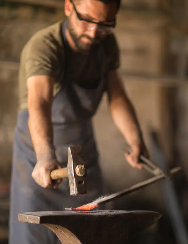 Blacksmith hammering glowing metal on an anvil