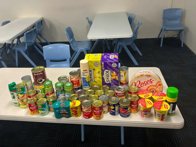 Table of tinned food and groceries ready to be packed into hampers