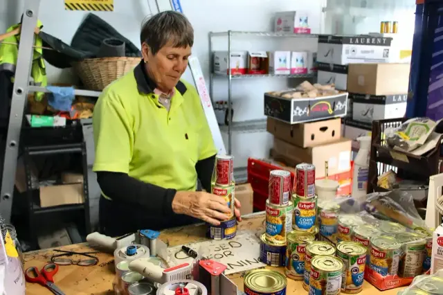 Goodness volunteer in a hi-vis shirt sorting donated tins