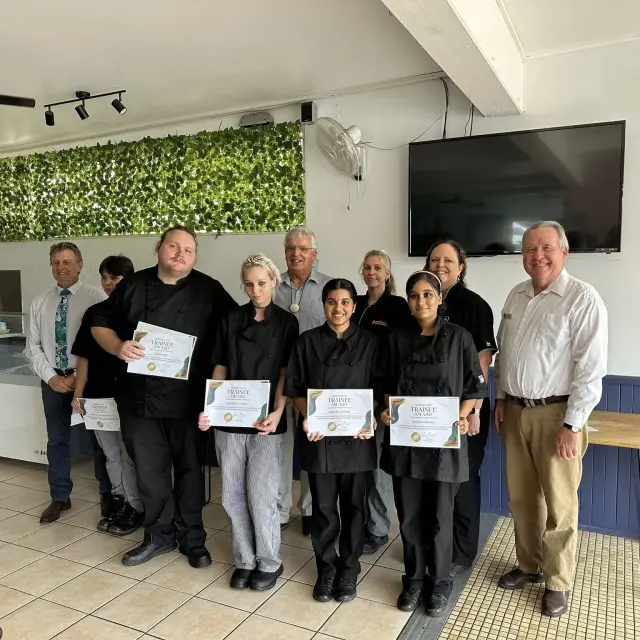 Goodness Enterprises staff and trainees in black uniforms holding their certificates in the training room