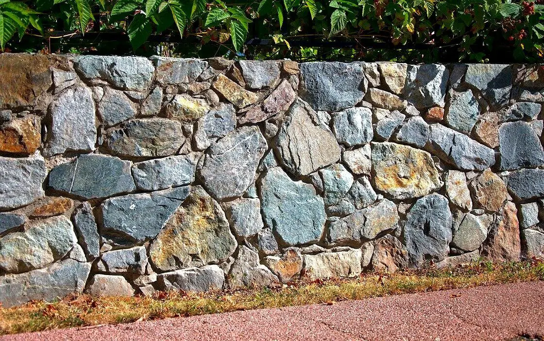 Dry laid fieldstone retaining wall along a gravel path