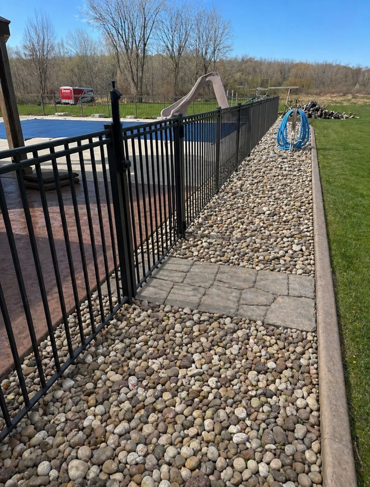 Fresh river rock along the pool fence with a clean paver border