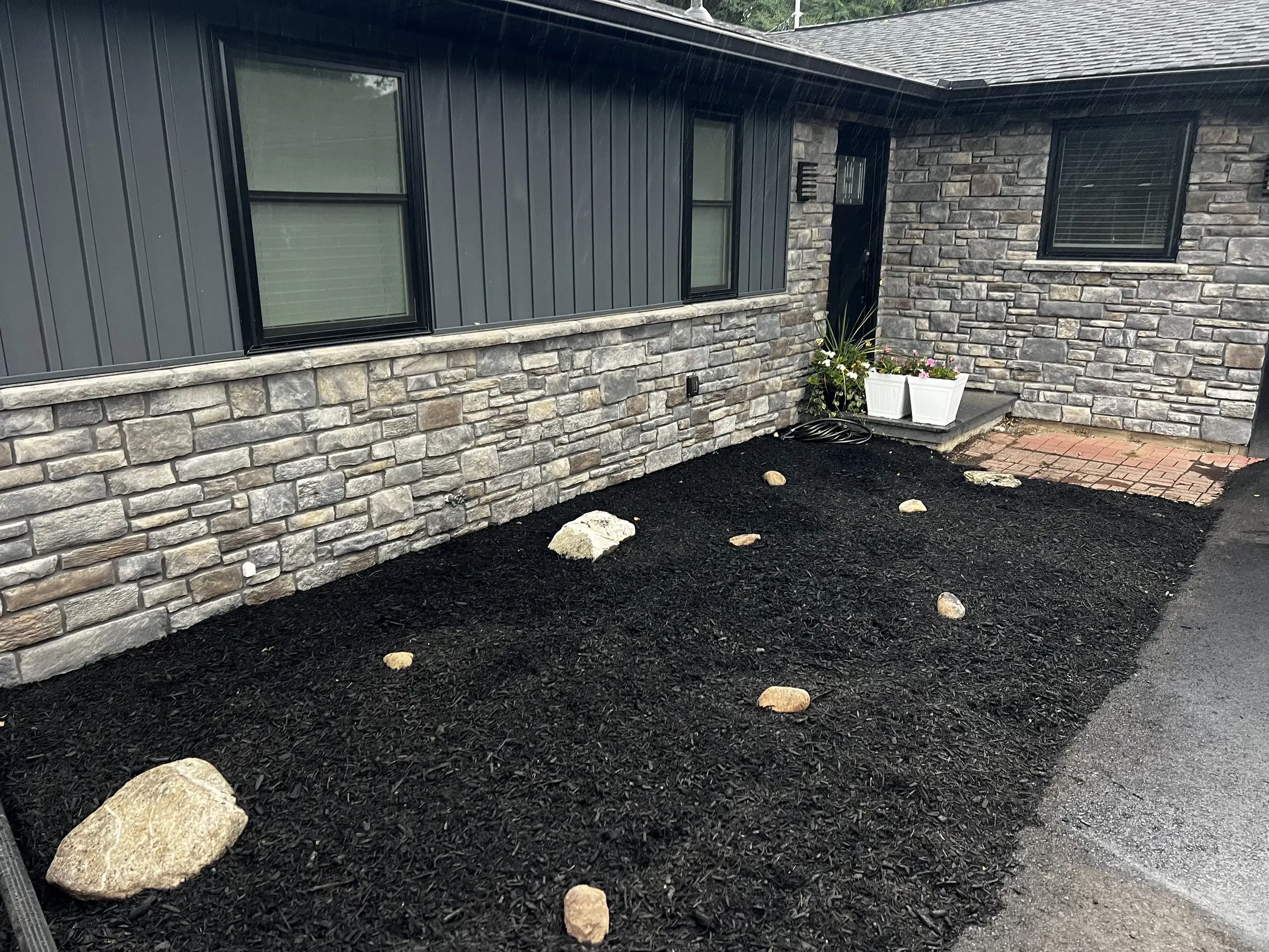 Front of the same house after: black mulch, boulders, clean edges