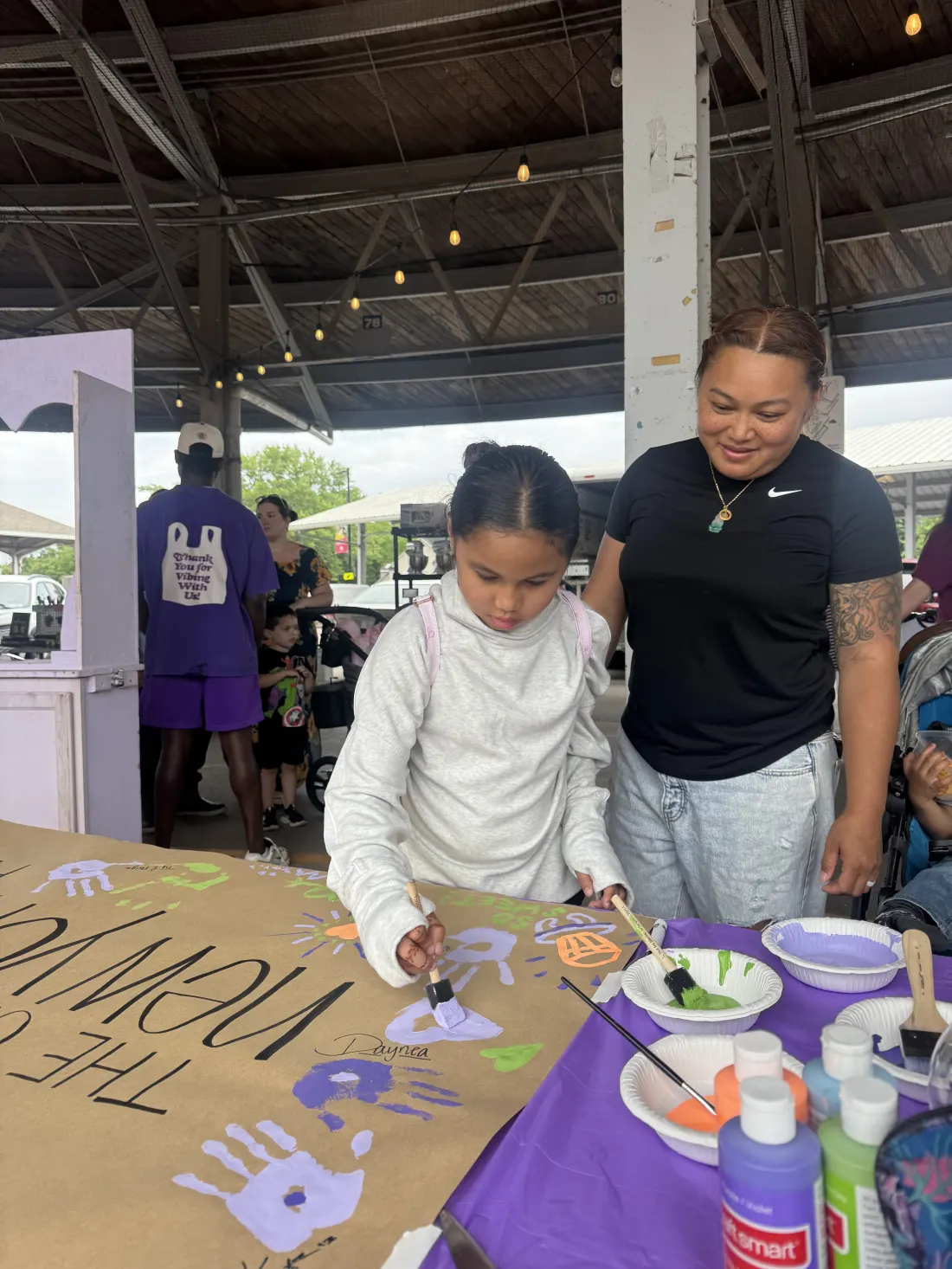 Child and adult painting a community banner together at the Flea