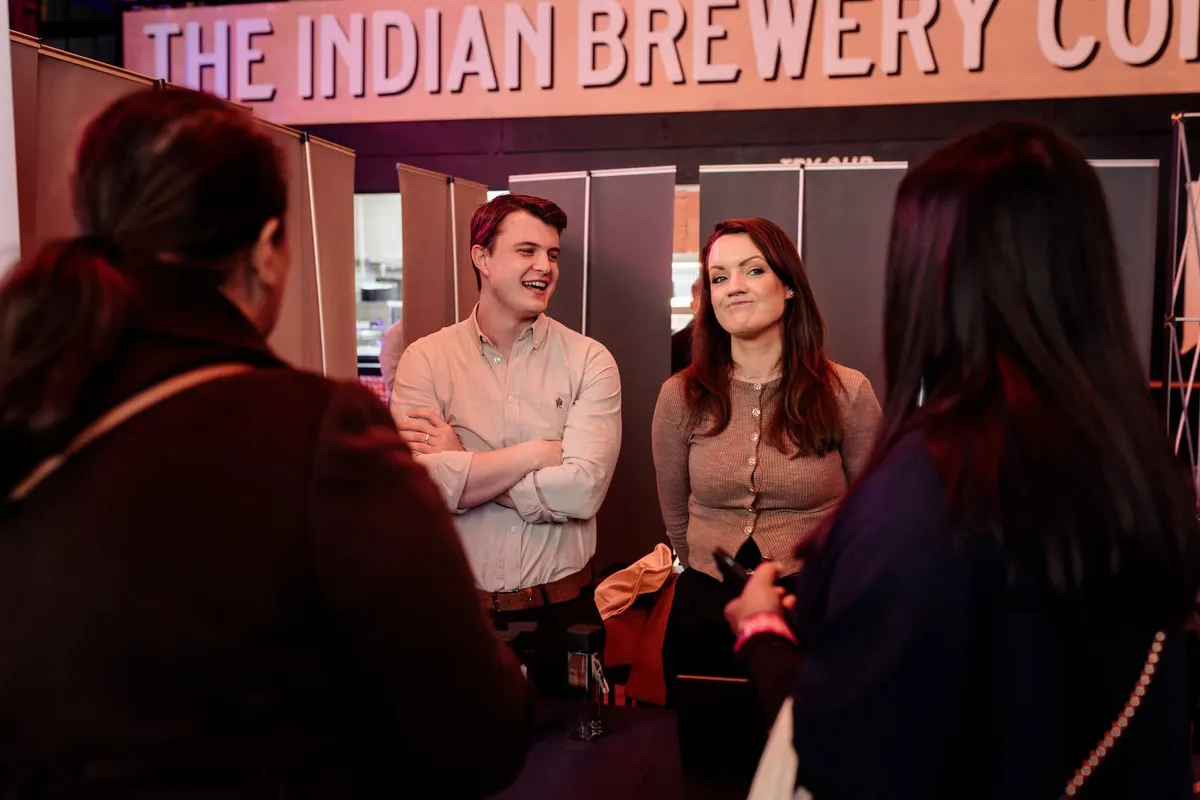 Guests laughing under the Indian Brewery sign at UK Homes Network LIVE Birmingham