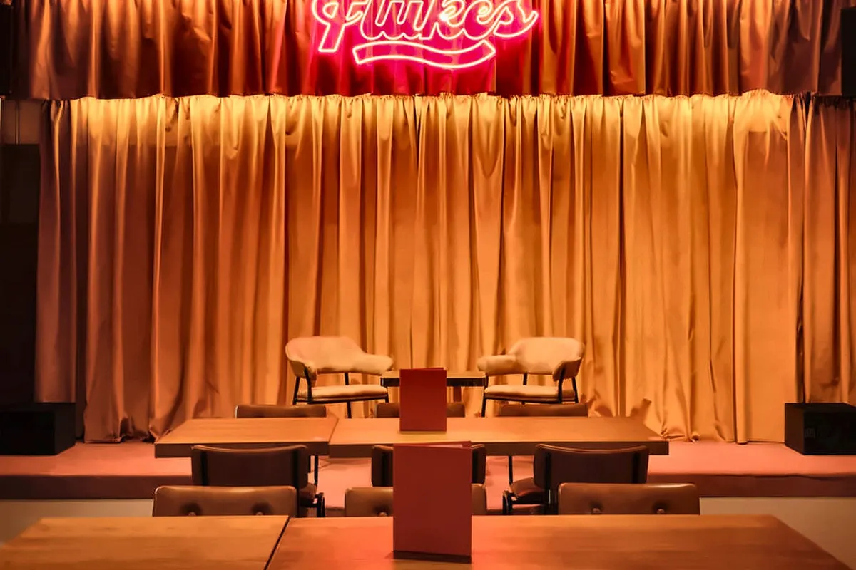The curtained stage under the neon sign at Flukes, Walthamstow