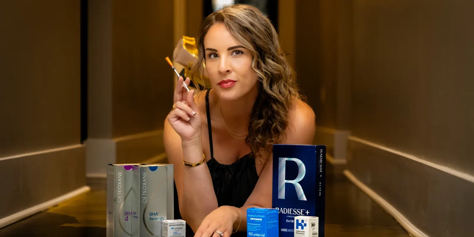 Nurse practitioner holding a syringe beside dermal filler and wrinkle relaxer products at Lexel med spa in Dunn, NC