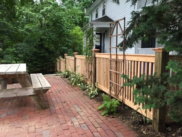 Wood fence beside a brick patio by All Fenced In