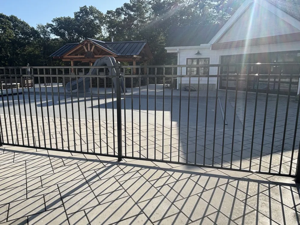 Black aluminum fence and gate around a pool patio by All Fenced In