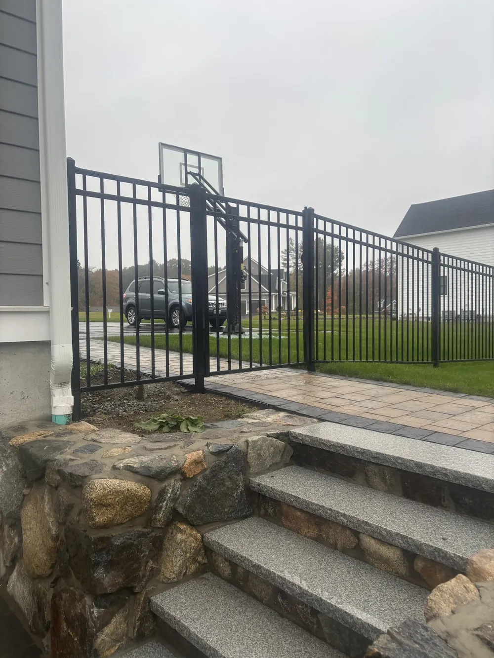 Black aluminum fence beside new stone steps by All Fenced In