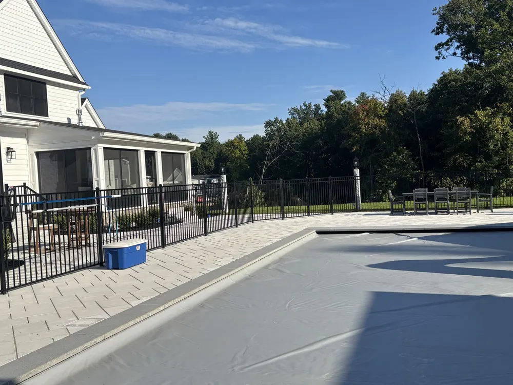 Black aluminum pool fence around a stone pool deck by All Fenced In