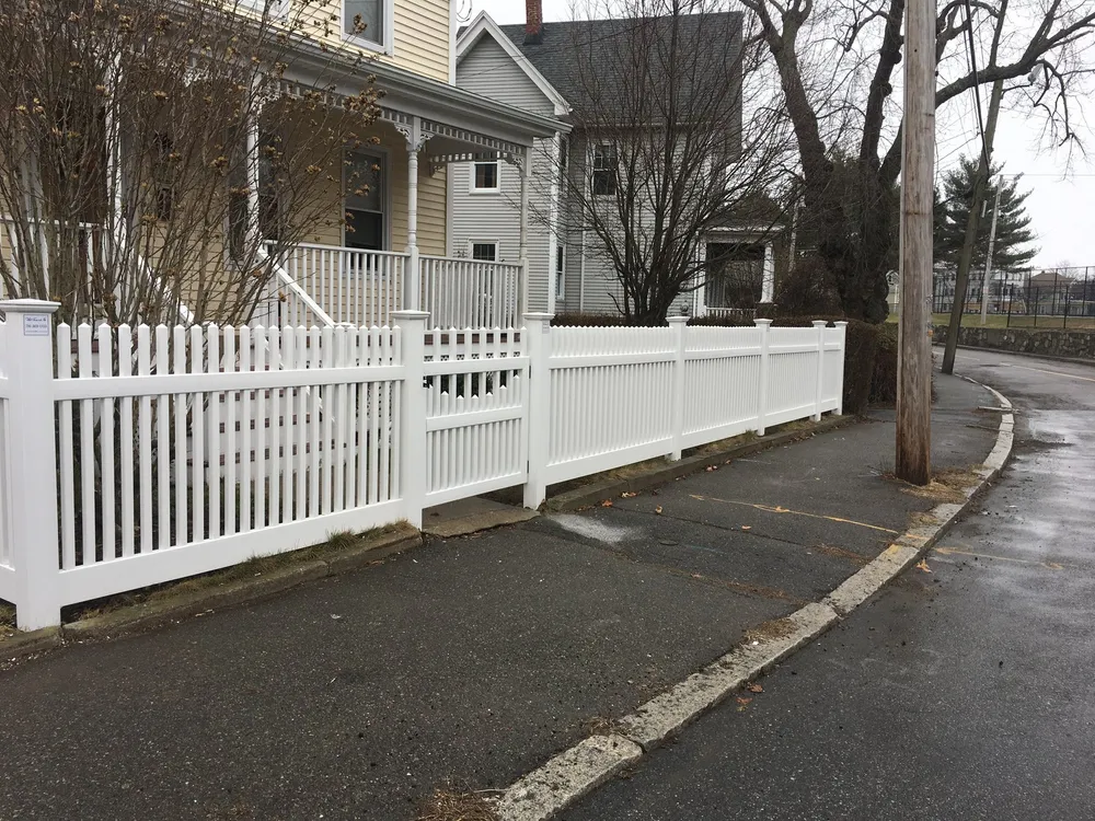 White vinyl picket fence along a sidewalk by All Fenced In