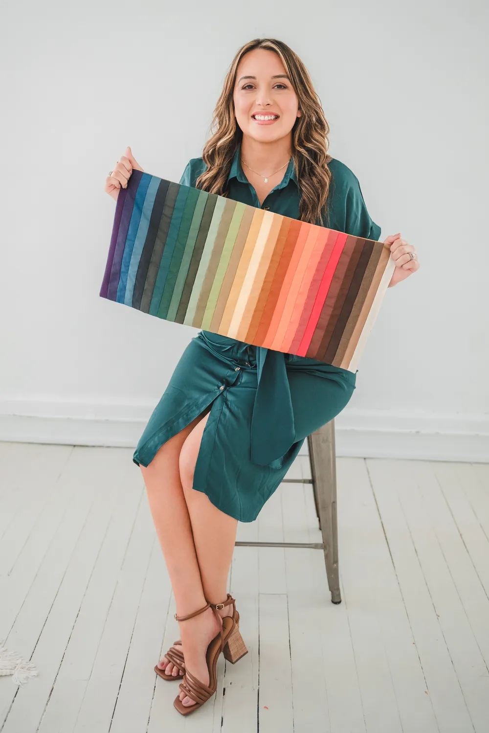 Bethany seated on a stool, holding a long drape of color swatches