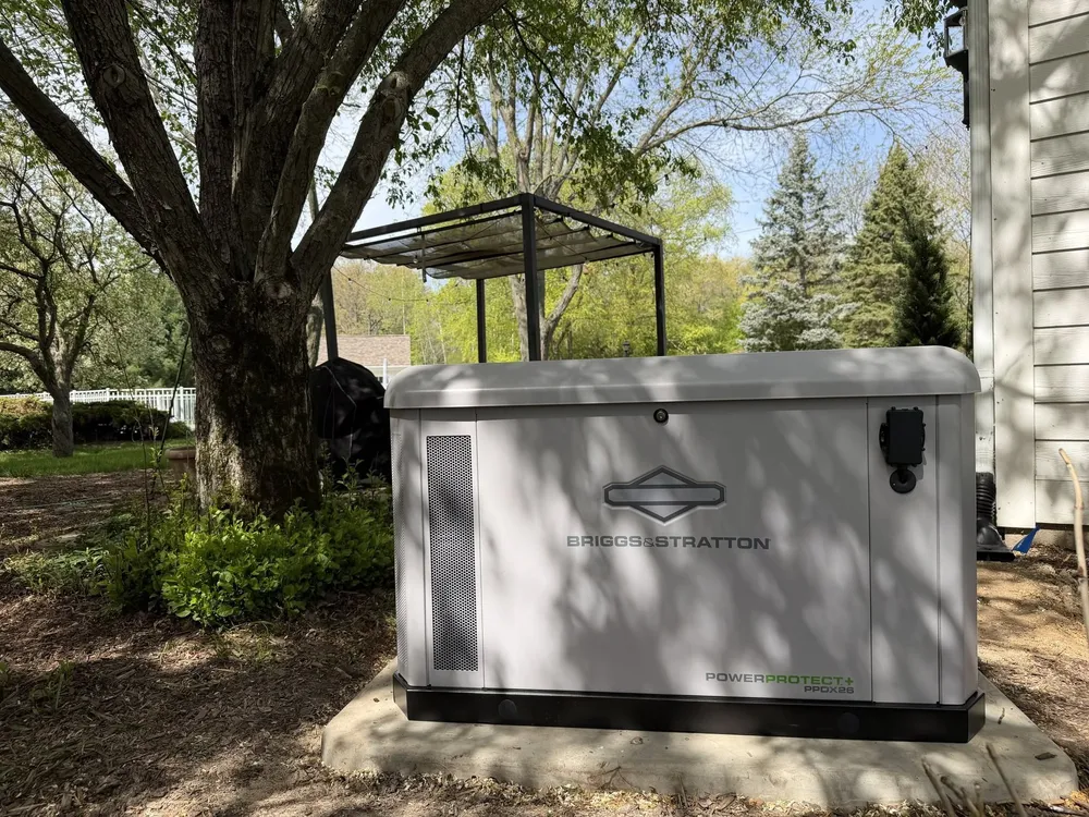 A whole-home standby generator installed on a concrete pad beside a Michigan home