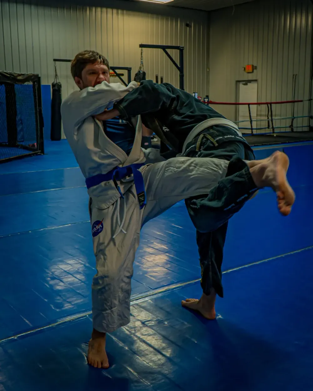Two partners working a standing drill beside the cage at Delta