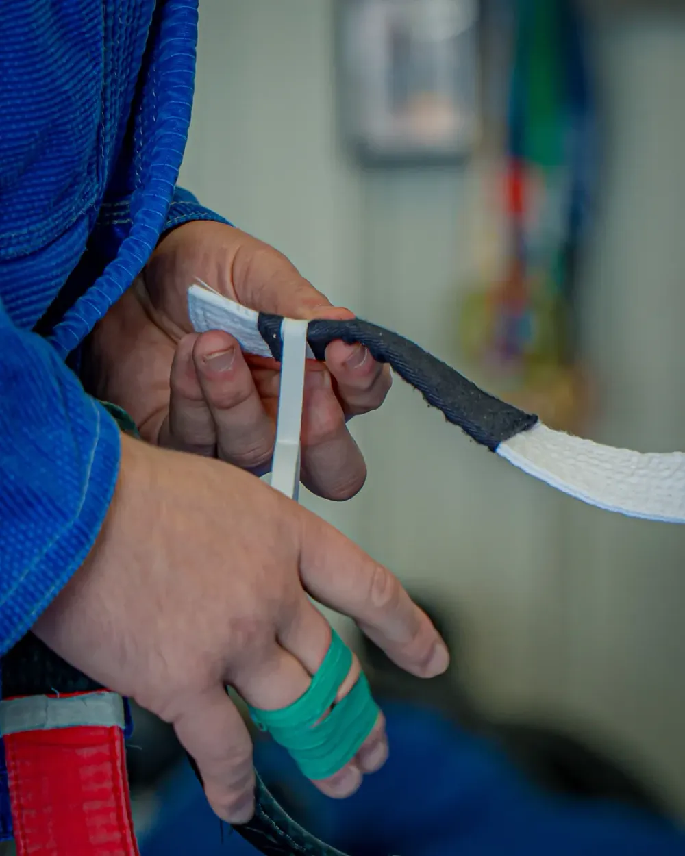 A coach taping a stripe onto a student's white belt