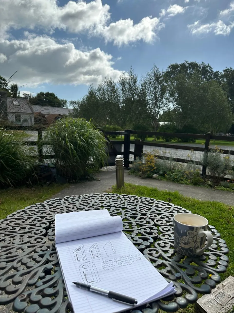 Sketching designs for awards at a garden table outside the studio