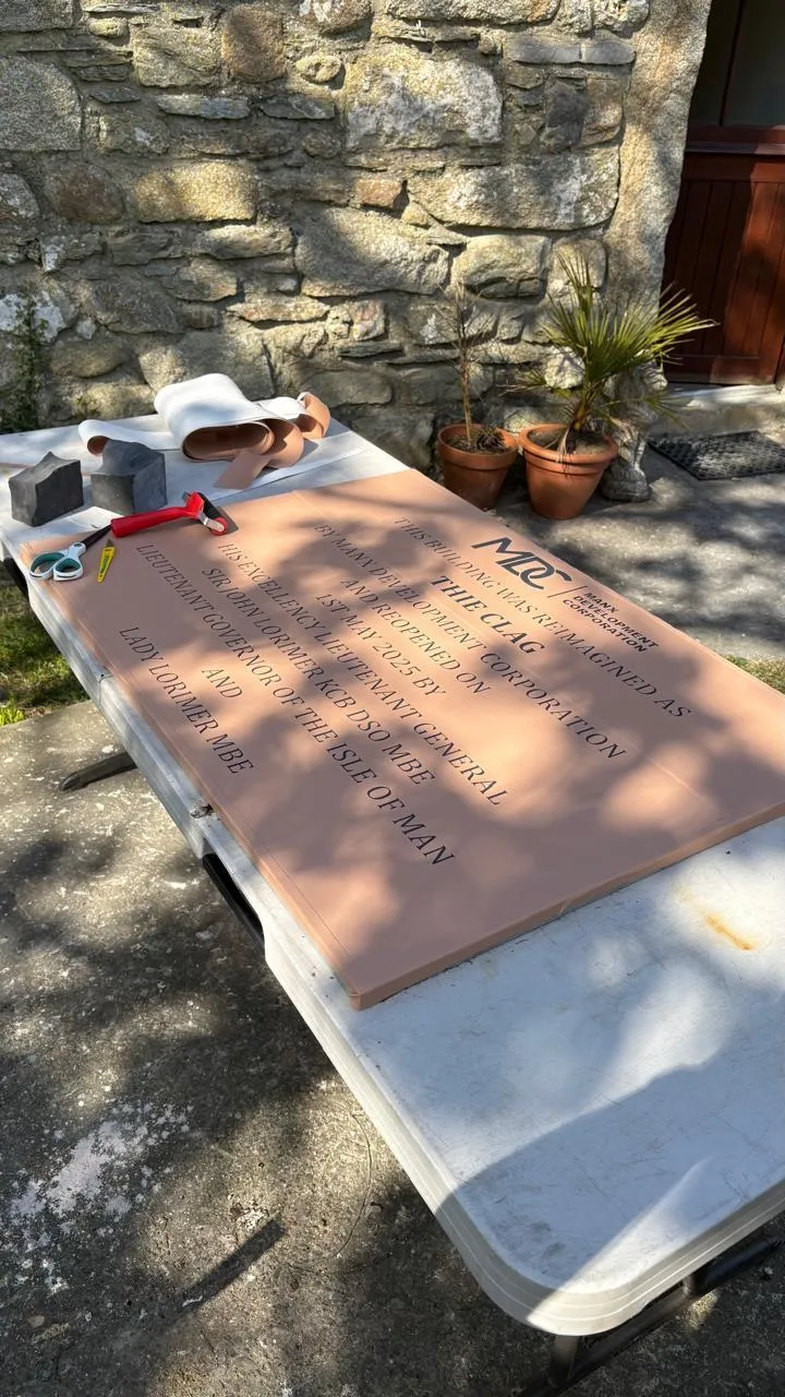 A large sandblasting stencil laid out on a table outside the studio