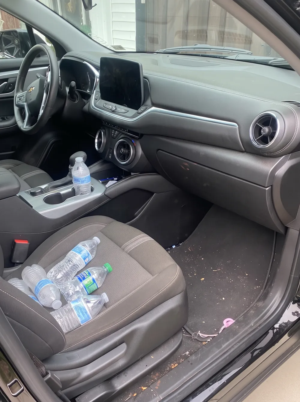 Black Chevy interior with empty water bottles and crumbs before an interior detail