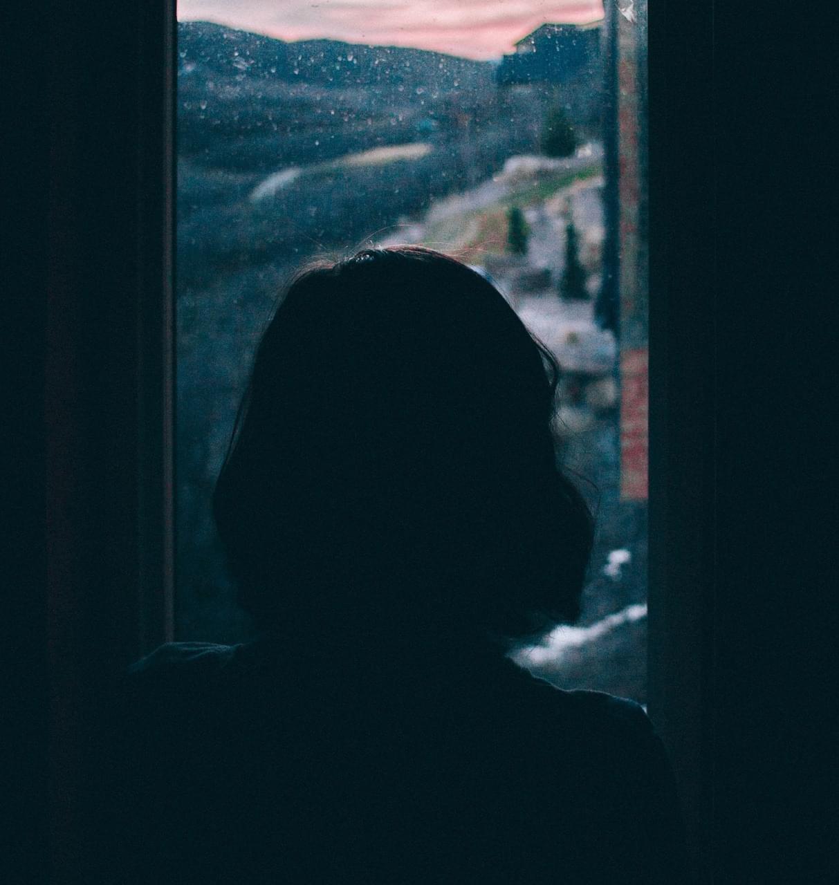 Une femme seule regarde par la fenêtre