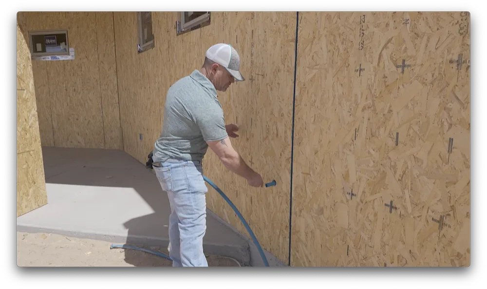 Jerome Maldonado running a line along the exterior sheathing of a new build