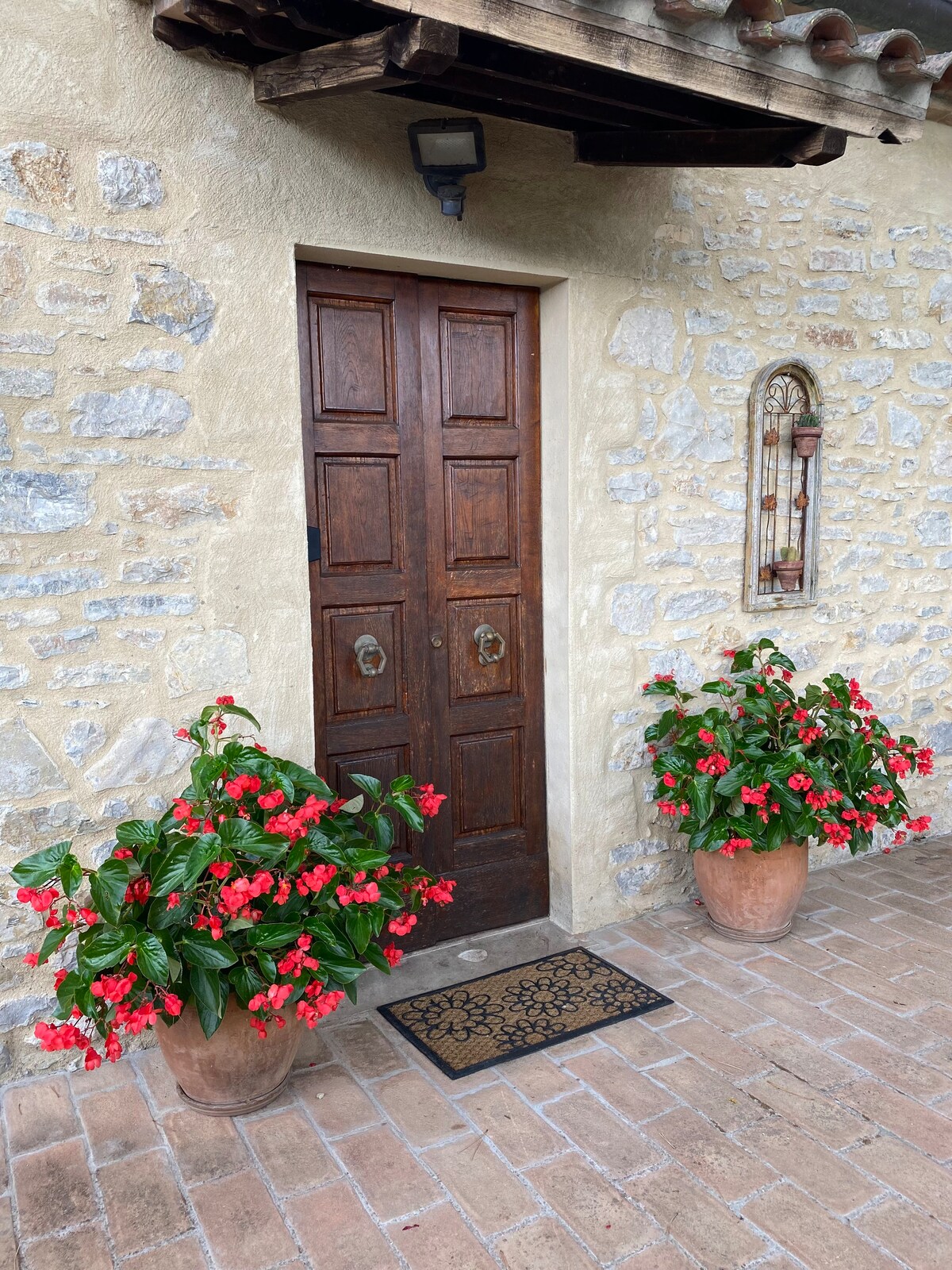Stone entrance to Villa Pregiata with wooden door and flowering pots
