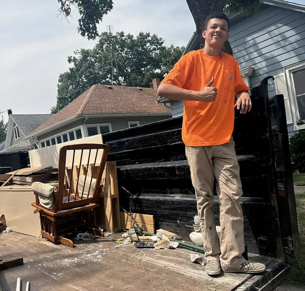Next Level Junk Removal crew member giving a thumbs up on a loaded trailer