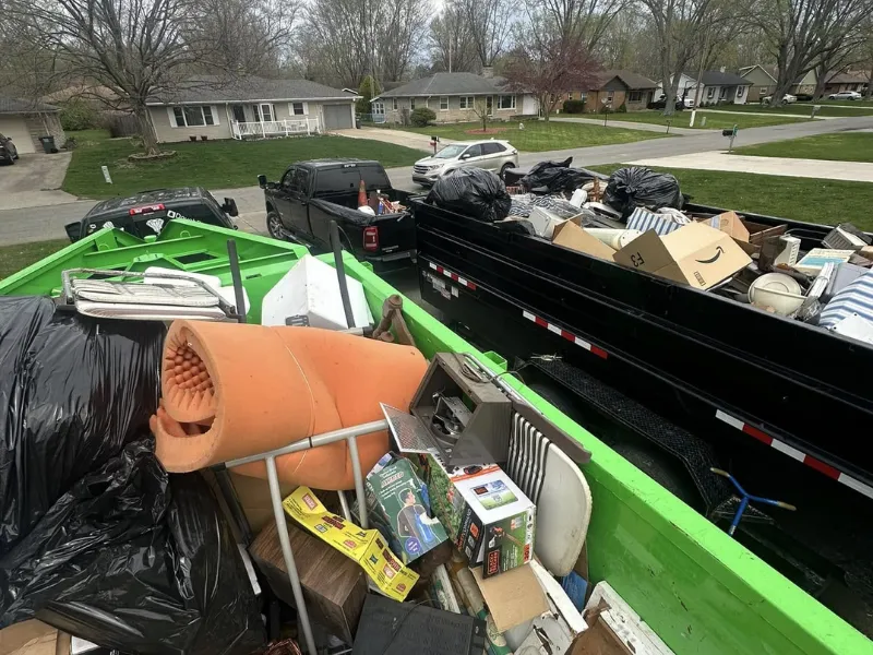Dumpster and dump trailer filled with items from a property cleanout