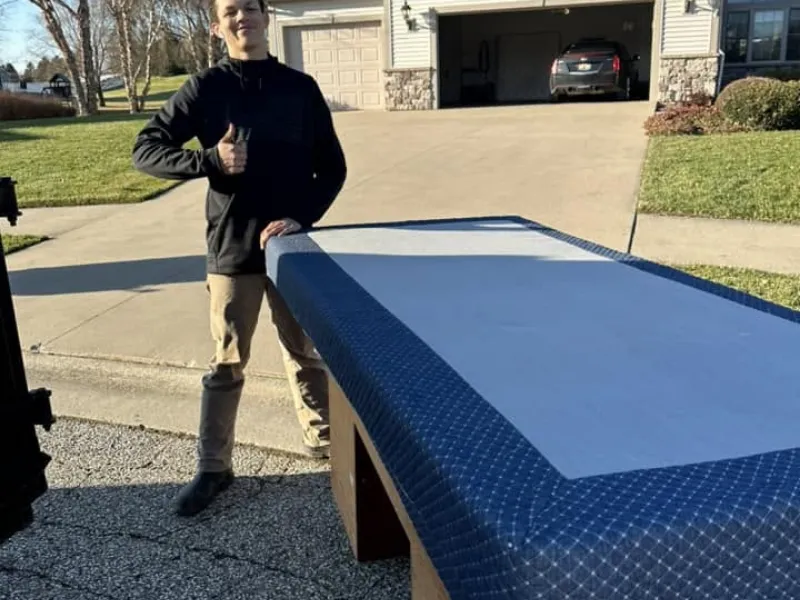 Crew member carrying out an old mattress for furniture removal