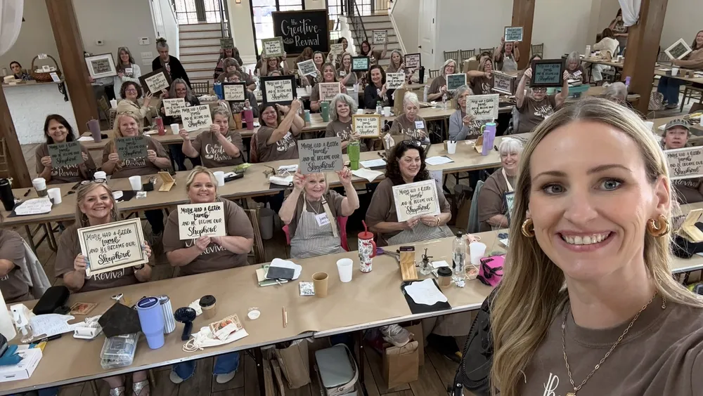 Danielle with a room full of workshop students holding their lettered signs
