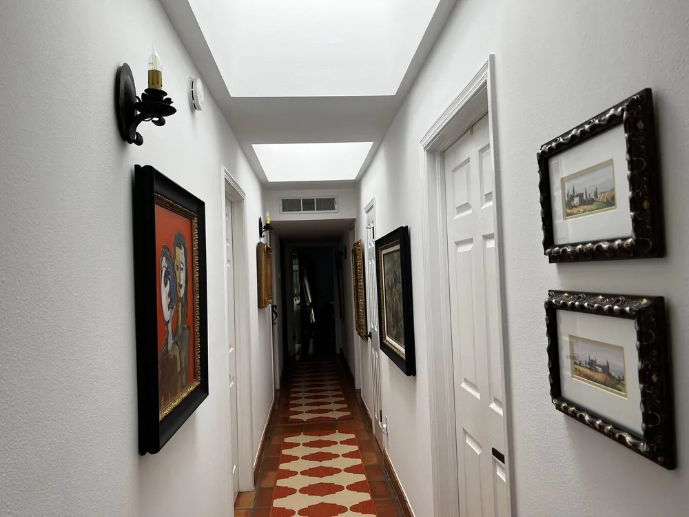Bright white hallway with skylights and framed art