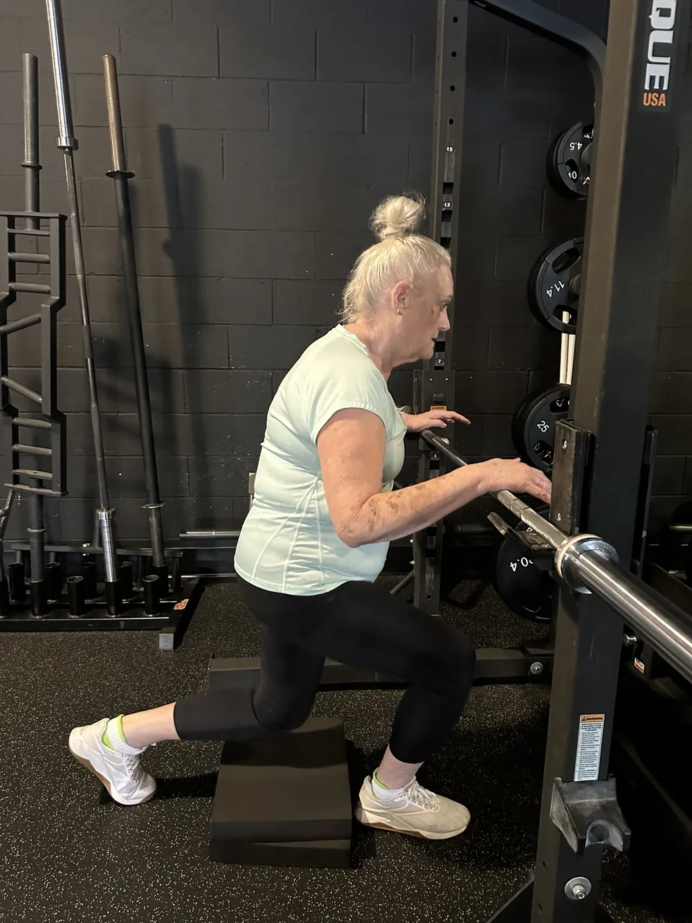 50 Strong client doing a supported split squat at the rack