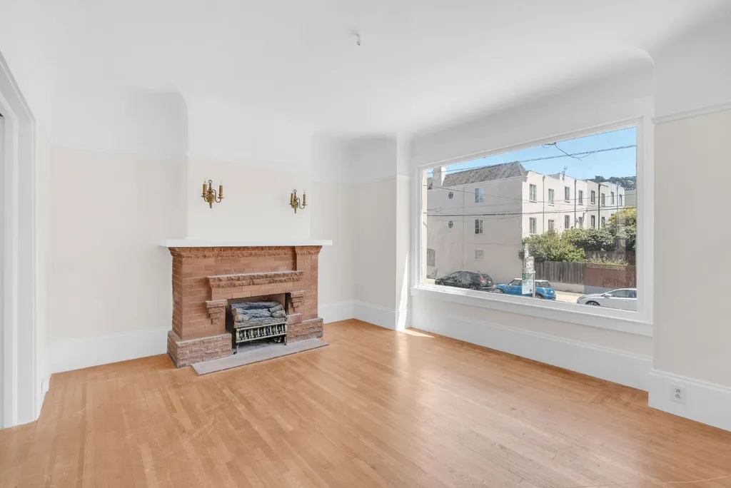 Living room with a brick fireplace and a large window to the street