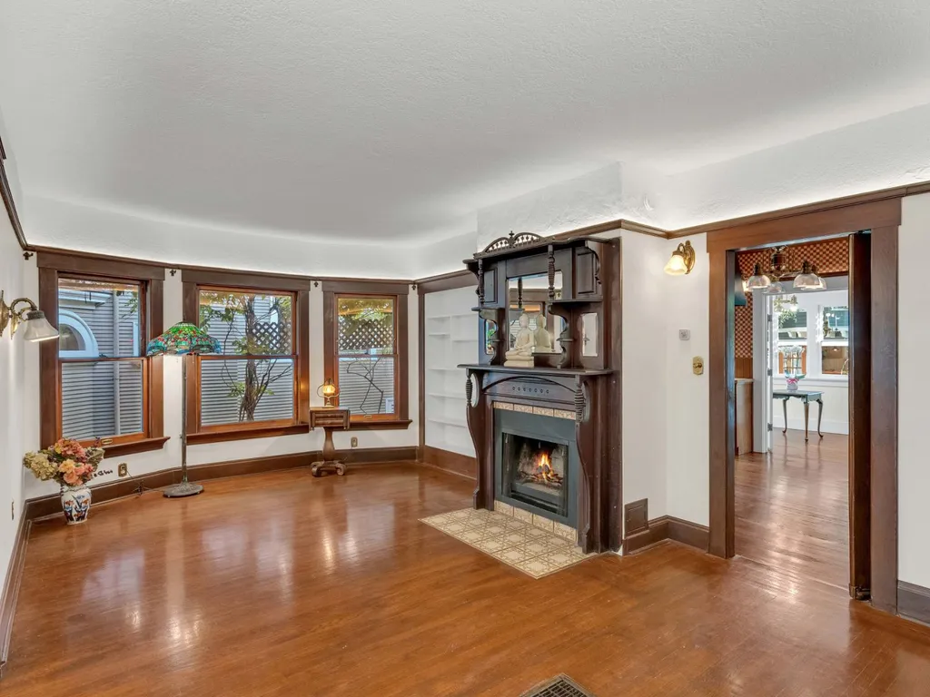 Living room with a carved wood fireplace and bay windows