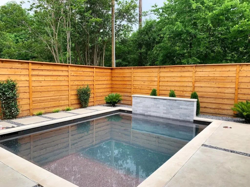 Horizontal cedar privacy fence around a backyard plunge pool with a stone water feature
