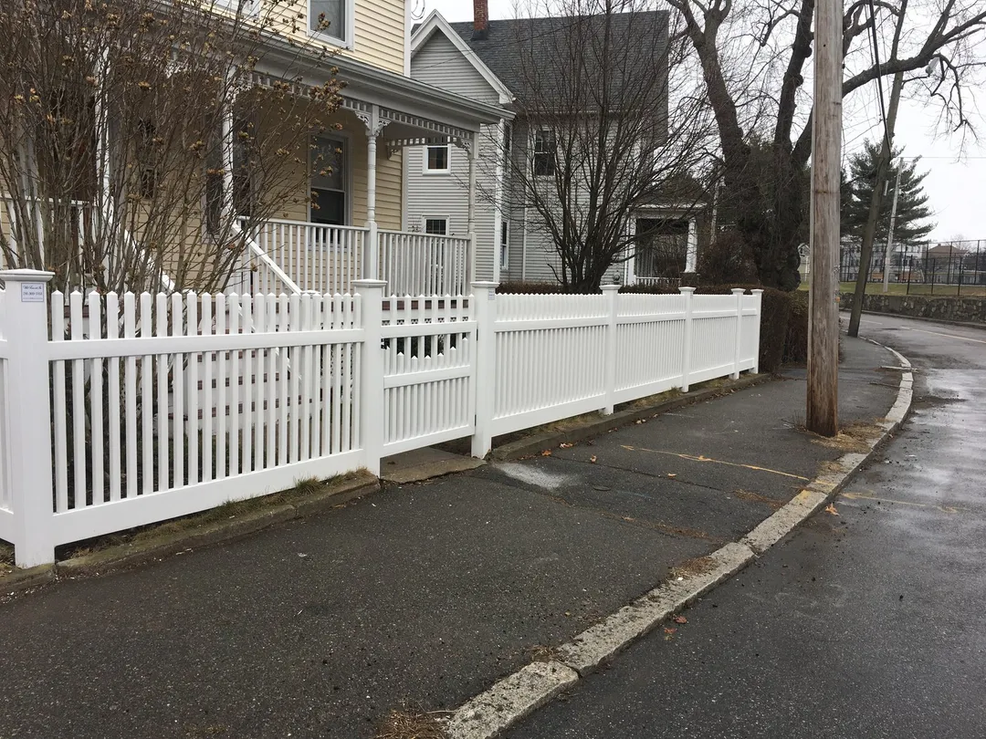 White vinyl picket fence along a sidewalk by All Fenced In