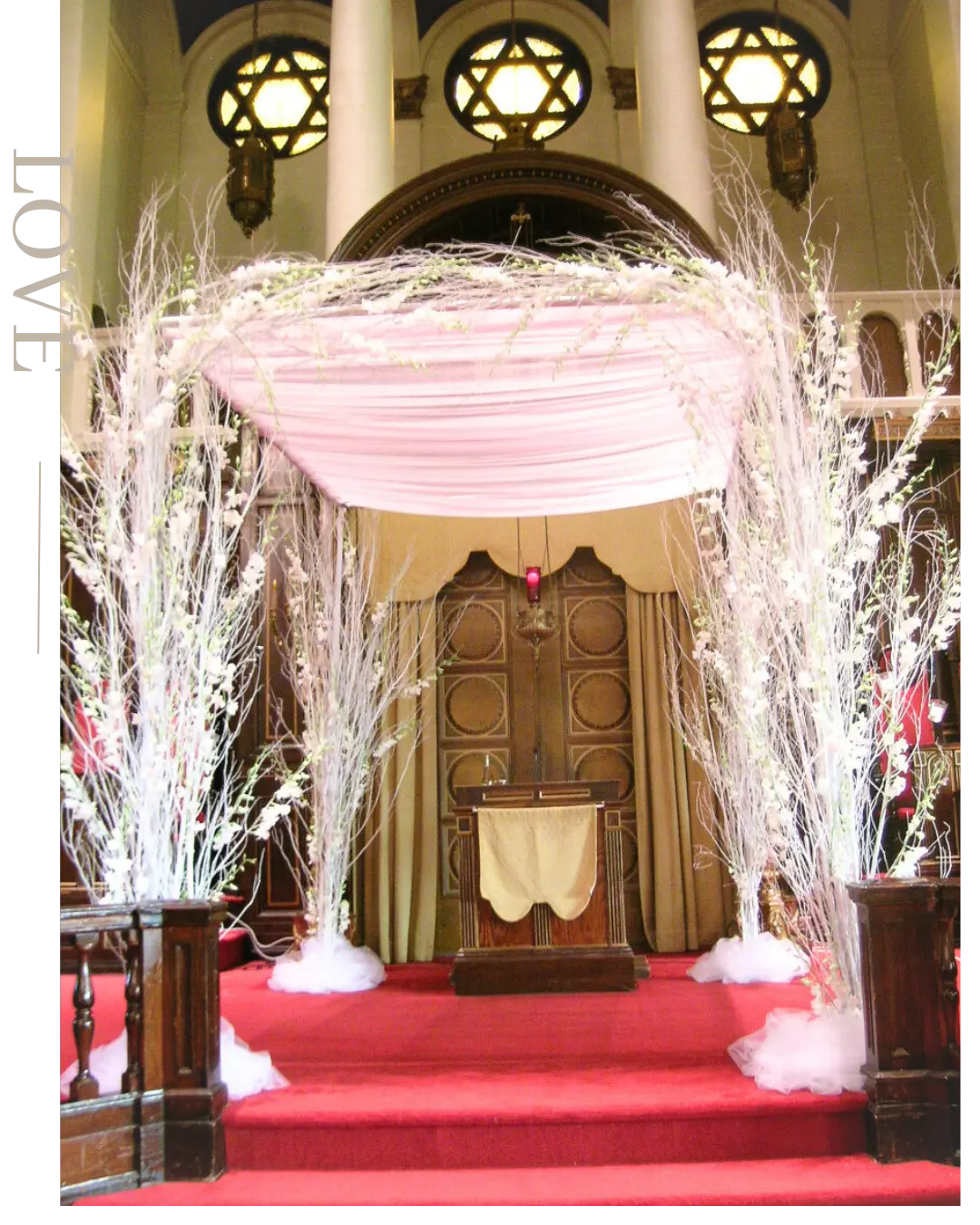 Chuppah aux branches blanches et dais rose poudré dans une synagogue