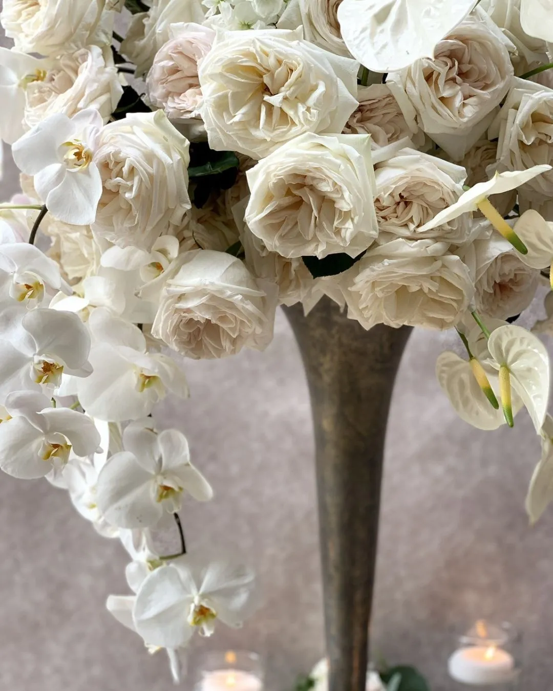 White garden rose and orchid arrangement in a tall vase