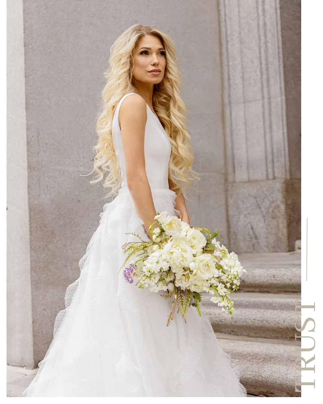 Mariée sur les marches d’une cathédrale avec un bouquet blanc et vert