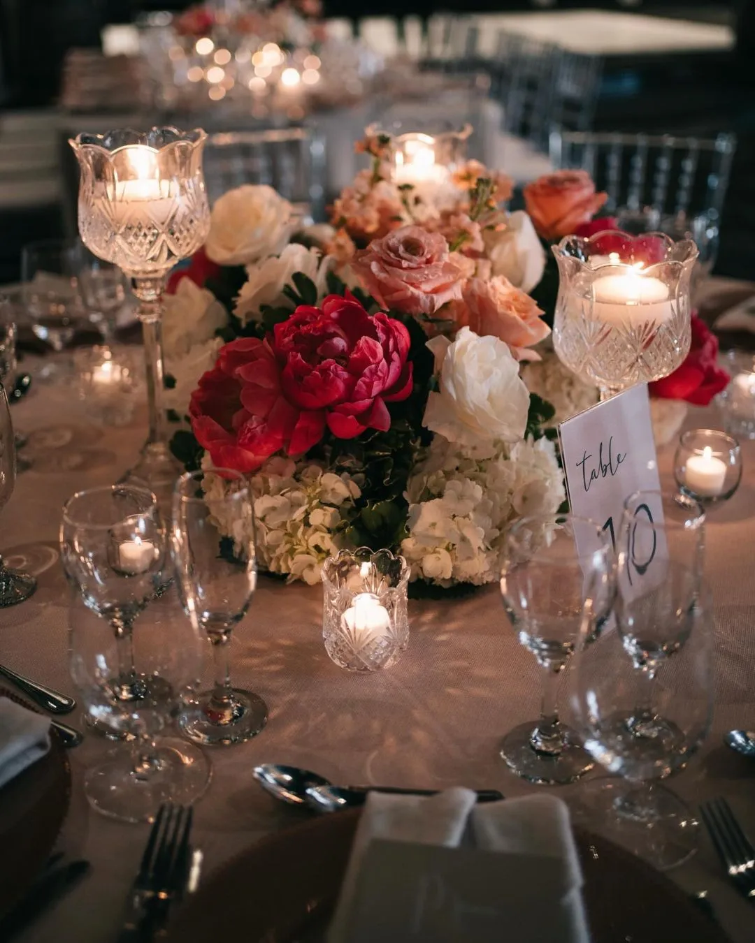Low centrepiece of red and blush roses surrounded by candles