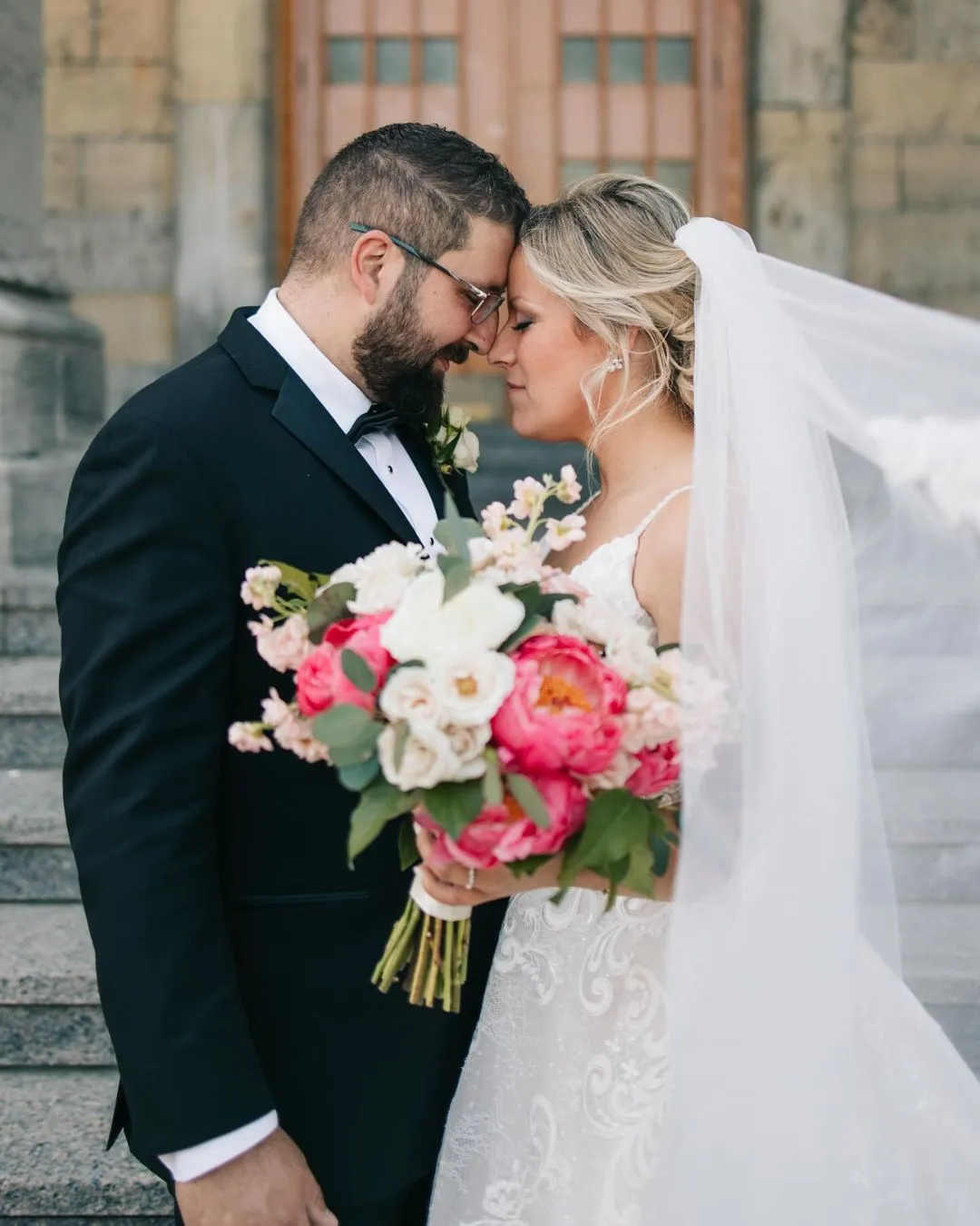 Newlyweds with a coral peony and white rose bouquet