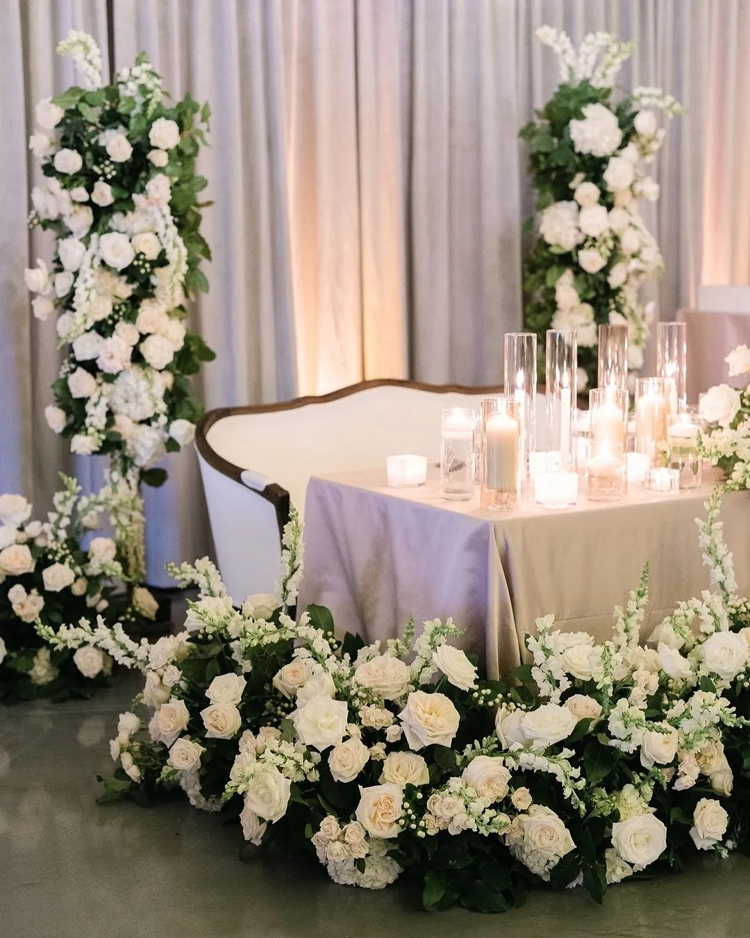White rose sweetheart table with floral columns and candles