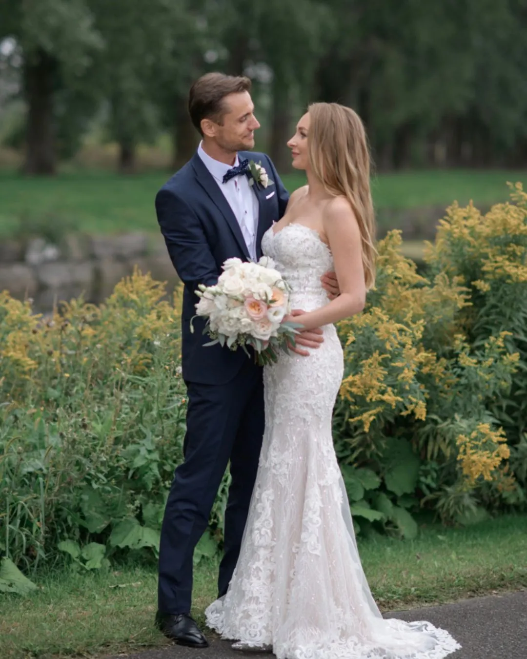 Bride and groom with a white rose bouquet in a garden