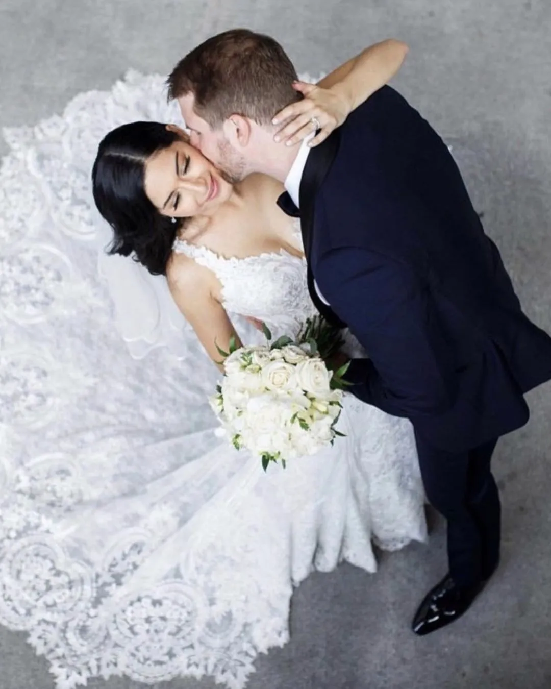 Groom kissing the bride holding a white bouquet