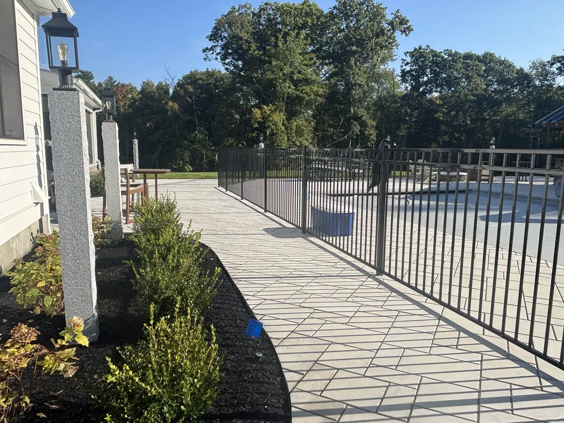 Black aluminum pool fence along a stone walkway in North Reading by All Fenced In
