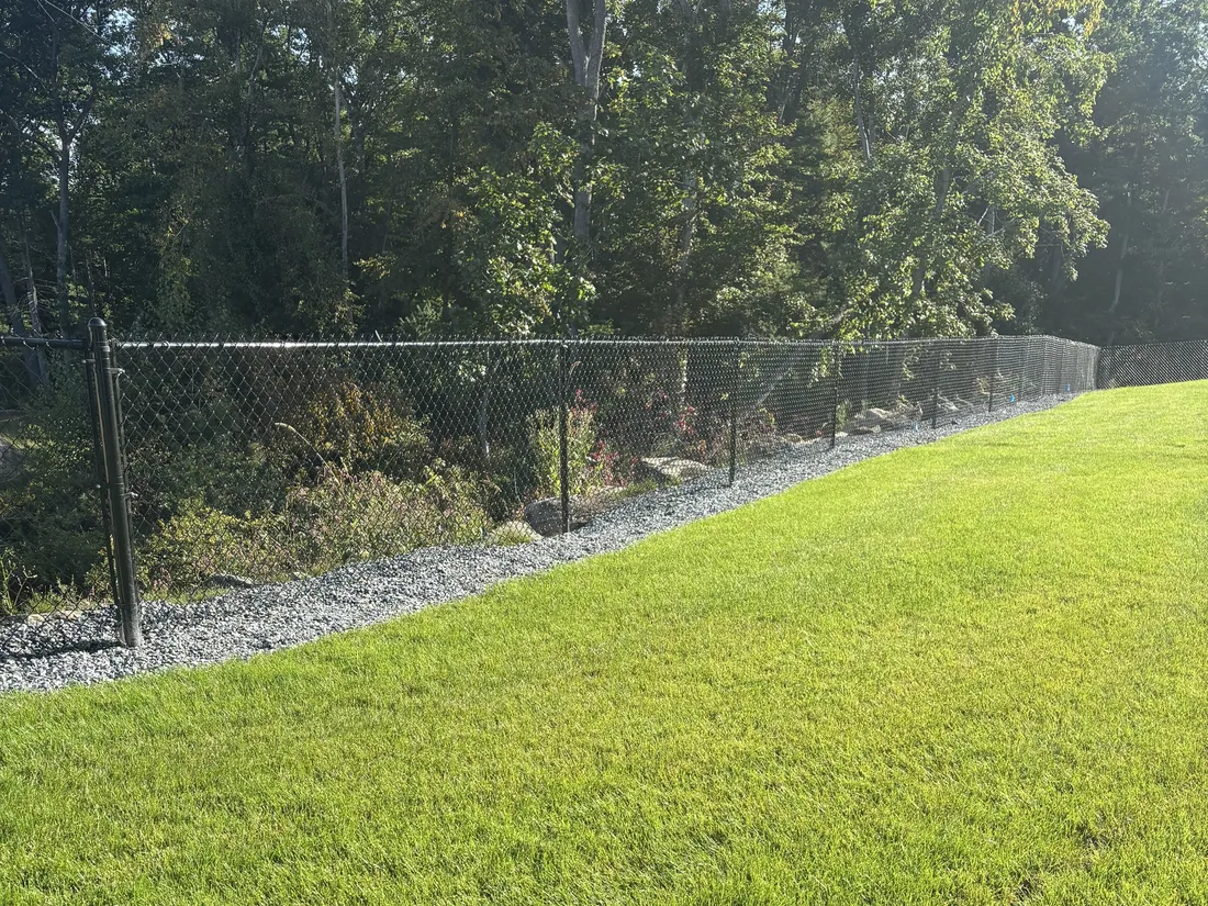 Black chain link fence along the wooded back of a property in North Reading by All Fenced In